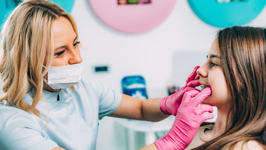 Orthodontisct controleert de beugel van een meisje.